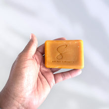 Load image into Gallery viewer, Hand holding a bar of soap with 'Secret Serenity' branding on a light background